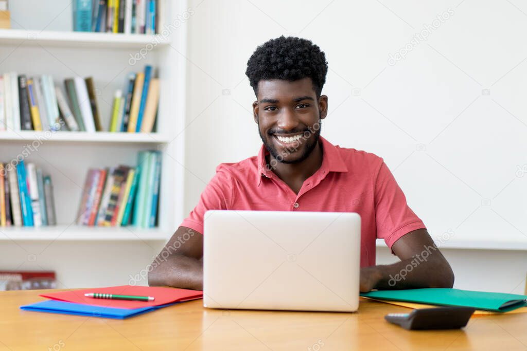 Handsome afro american male student learning at computer indoors at home
