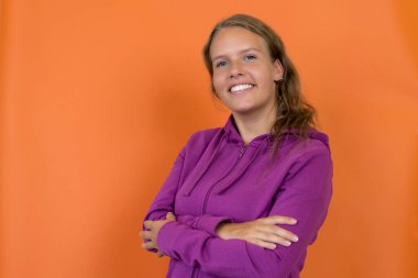 Turuncu arka planda kapüşonlu, sarışın, genç, güzel bir kadın.