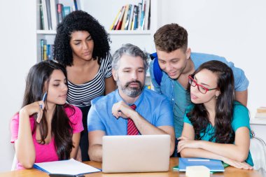 Öğretmen bilgisayar bilimleri öğrencileriyle üniversitenin sınıfında yazılımın programlanması ve kodlanması hakkında konuşuyor