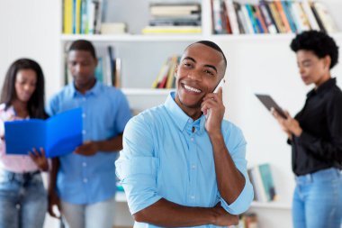 Ofisteki bir grup siyahi iş adamıyla telefonda konuşan Afrikalı Amerikalı iş adamı.
