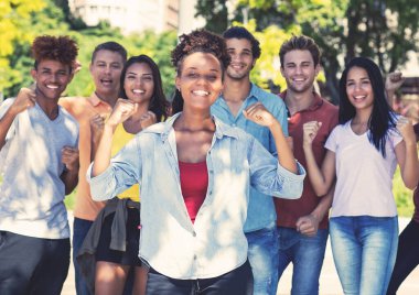 Güzel Afro-Amerikan bayan öğrencisi ve bir grup neşeli genç yetişkin yazın şehir dışında.