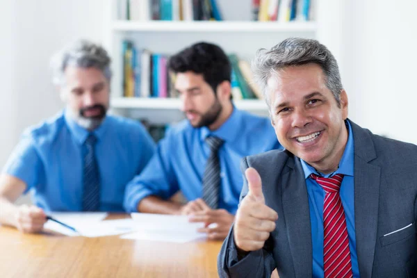 Successful elderly businessman with motivated team at office of company