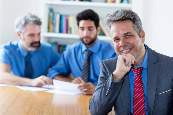 Handsome elderly businessman with motivated team at office of company