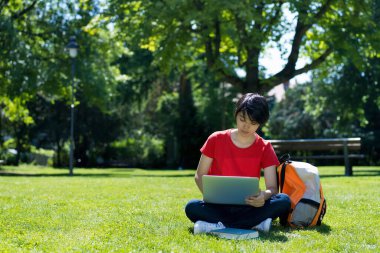 Koreli erkek öğrenci yazın üniversitenin açık hava kampüsünde bilgisayar eğitimi alıyor.