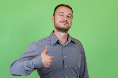 Sakallı bir İngiliz yeşil arka planda başparmak gösteriyor. 