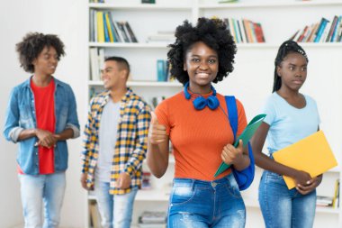 Üniversitenin kütüphanesinde bir grup siyahi genç yetişkin ile başarılı afro-amerikan bayan öğrenci.
