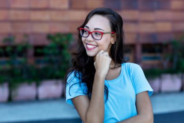 Uzun siyah saçlı, güzel bir genç kadın. Şehirde gözlük takıyor.