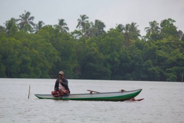 Sri Lanka nehri, Srilankan turizmi, alacakaranlıkta, Srilankan kültüründe ve turizmde balıkçılık yaparken göl balıkçılığı yapan balıkçı..