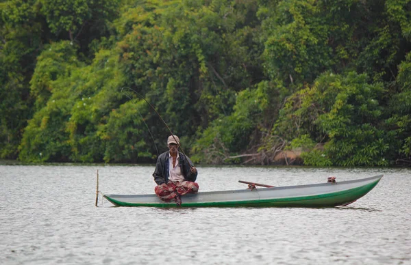 Rivière Sri Lankaise, tourisme srilankan, Pêcheur du lac en action lors de la pêche au crépuscule, culture et tourisme Srilankan.Bateau en bois avec canne à pêche. — Photo