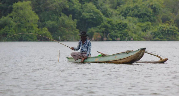 Râul Sri Lanka, turismul srilankan, Pescarul lacului în acțiune atunci când pescuiește pe amurg, cultura Srilankan și turism.barcă de lemn cu tijă de pescuit . — Fotografie, imagine de stoc