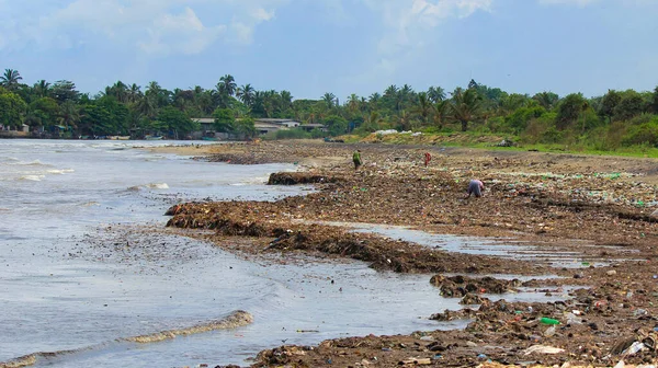 Poluarea mării: gunoiul aruncat în Marea Sri Lanka lângă Colombo. Femeile colectează lucruri din plastic într-o grămadă de gunoi aduse de surf din mare — Fotografie, imagine de stoc