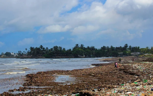 Sea Pollution: Garbage dumped in the Sri Lankan Sea near Colombo. women collects plastic things in a pile of garbage brought by the surf from the sea