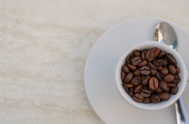 Beyaz arka planda kahve fincanı ve fasulye. Metin girdisi için kopyalama alanı olan üst görünüm.