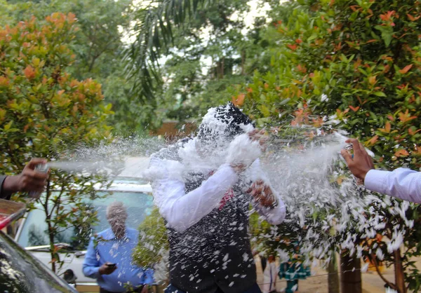 spraying the groom with party snow spray during wedding function