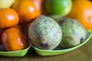 yeşil bir tabak üzerinde mandalina ile armut.