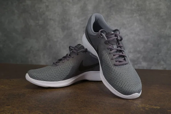 Tallinn, Estonia - 9.09.2019: Lanzamiento de zapatillas Nike para hombre. Nike revolución 4 sobre marrón - fondo gris —  Fotos de Stock