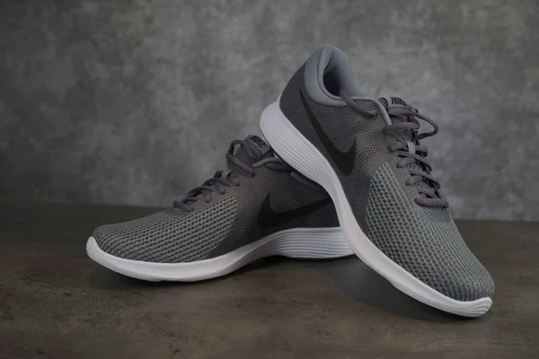 Tallinn, Estonia - 9.09.2019: Lanzamiento de zapatillas Nike para hombre. Nike revolución 4 sobre marrón - fondo gris —  Fotos de Stock