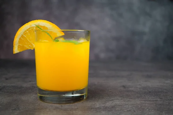 Ein Glas frischer Orangensaft auf grauem Hintergrund. — Stockfoto