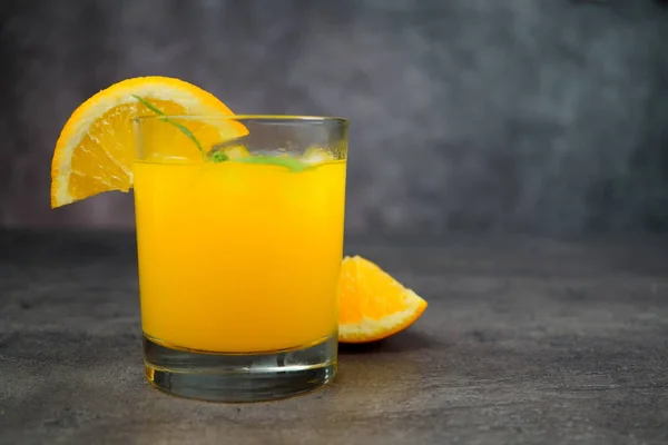 Un vaso de zumo de naranja fresco sobre fondo gris . — Foto de Stock