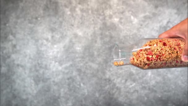 Éruption muesli d'une bouteille transparente sur un fond gris — Video