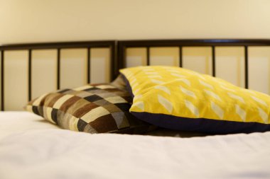 Renkli yastıklı bir otel odasında metal bir yatak.