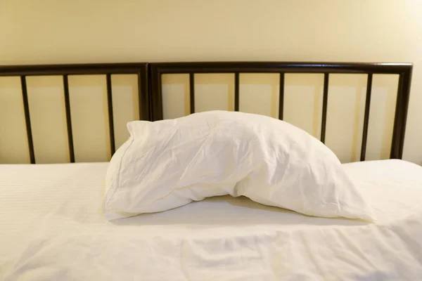 Metal bed in a hotel room with single white pillow — Stock Photo, Image