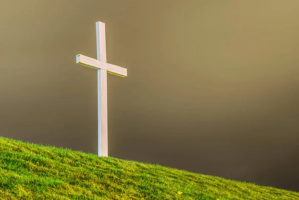 White wooden cross on green grass with copy space