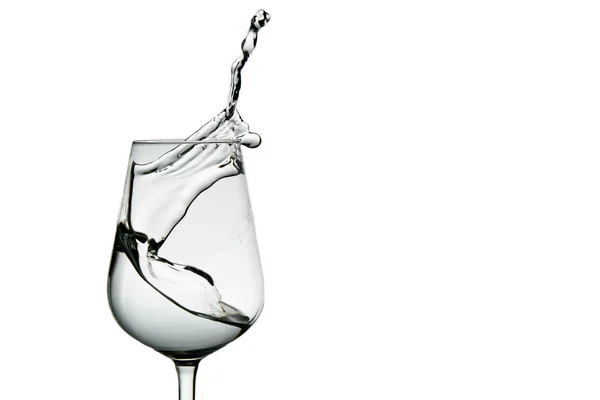 Mooie spatten water in een wijnglas, isoleren op wit, close-up met kopieerruimte. — Stockfoto