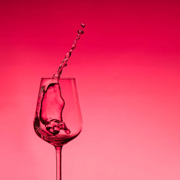 Schöne Spritzer Wasser in einem Weinglas, mit rotem Filter, Nahaufnahme mit Kopierraum. — Stockfoto