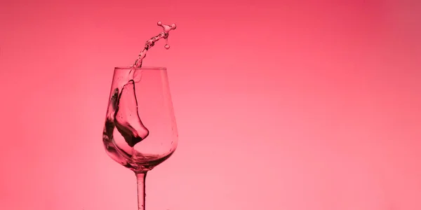 Bellissimi spruzzi d'acqua in un bicchiere di vino, con filtro rosso, da vicino con spazio per copiare . — Foto Stock
