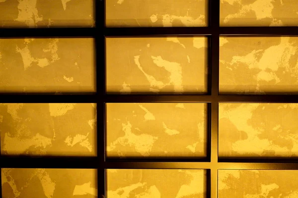 Rejilla rectangular de metal negro en la pared, con un fondo dorado . — Foto de Stock