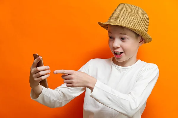 Distanciamento social e conceito de comunicação on-line, menino feliz conversando com amigo por smartphone no fundo da parede laranja. Felicidade no conceito de distanciamento . — Fotografia de Stock