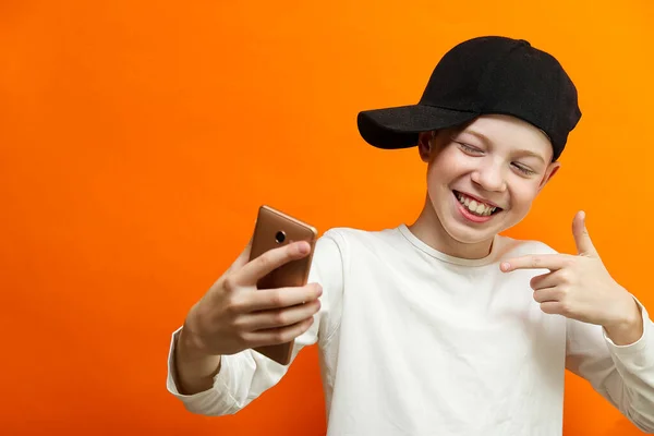 Distance sociale et concept de communication en ligne, Happy boy Chatter avec un ami par smartphone sur fond de mur orange. Le bonheur dans le concept de distance . — Photo