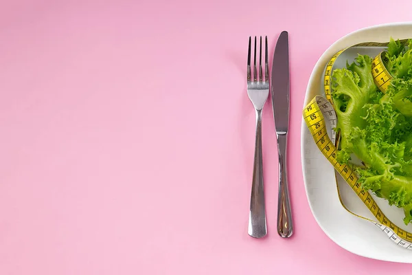 Bunch of vegetables isolated on pink background. salad tape weight. Pile of fresh vegetables with measuring tape. Green vegetable smoothie.