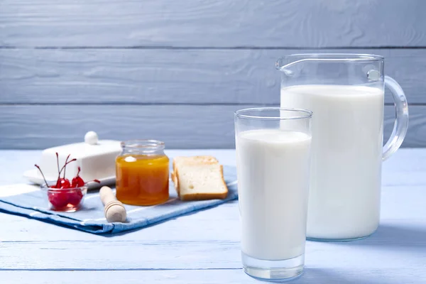 Brocca e bicchiere di latte su fondo di legno blu con biscotti . — Foto Stock