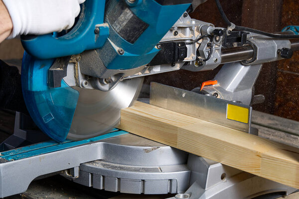 Closeup of professional cabinet makers working with electric circular saw at woodworking workshop. Skilled carpenter cutting wooden board with circular saw. Wood material production. Lumber factory