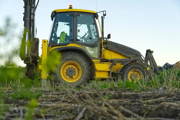 Pelle jaune. tracteur jaune sur le terrain. Machines de construction sur le terrain. grande chargeuse sur pneus jaune aligne un morceau de terrain pour un nouveau bâtiment. Tracteur sur les terres agricoles . — Photo