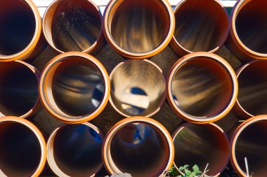 Bir inşaat alanındaki turuncu kanalizasyon boruları. Yeraltı turuncu plastik boruları. Yığılmış PVC turuncu borular.