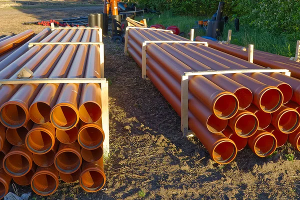 orange sewer pipes at a construction site. Underground orange plastic pipes. Stacked PVC orange pipes.