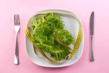 Pembe arka planda bir sürü sebze. Salata bant ağırlığı. Bir yığın taze sebze salatası ve mezura..