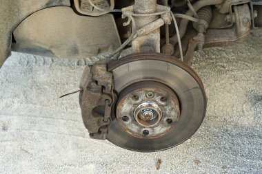 Tamir için aracın eski ve kirli arka kırığı. Tekerleği sökülmüş bir arabanın frenleri. Arabaların detaylı görüntüsü onarımdan önce bozulur.