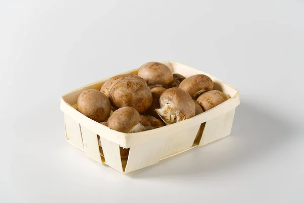 Brown Mushrooms champignons in wooden basket on a light background. Close up. Packed champignons to basket. — Stock Photo, Image