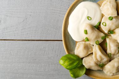 Ahşap zemin üzerinde ekşi kremayla servis edilen taze haşlanmış et köfteleri..