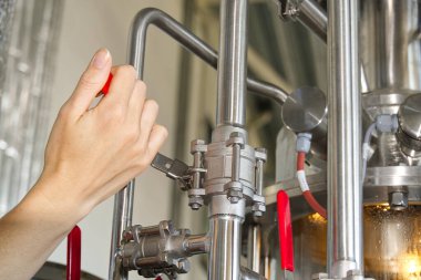 Fabrikada ve endüstriyel üretim tesisinde içecek üretimine yönelik ters su akışını önlemek için el ile açılan kırmızı kapı vanası..