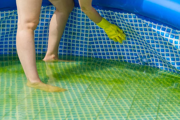 Cleaning pvc inflatable swimming pool, Cleaning the dirty empty pool of algae, The beginning of the swimming season in the hot summer. Cleaning service concept.