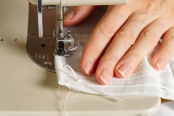 En kvinna jobbar på en symaskin. sömmerska syr vita gardiner, närbild. — Stockfoto