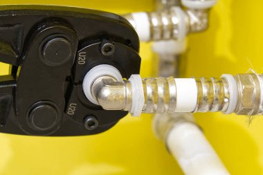 Alupex borularını musluğa bağlayan bir işçi. PEX-AL-PE-X su boruları için el presi. tesisat endüstrisi.