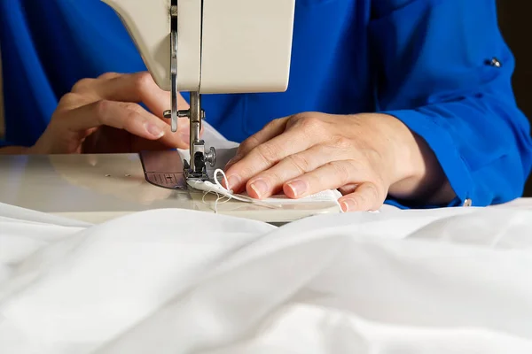 En kvinna jobbar på en symaskin. sömmerska syr vita gardiner, närbild. — Stockfoto