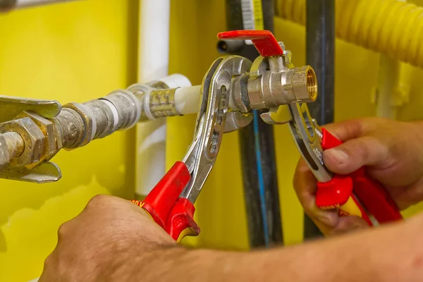 Raccorder les raccords de plomberie avec les clés. Le plombier assemble une nouvelle connexion d'eau à l'évier. — Photo