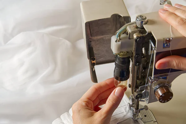 Kvinnan ställer in symaskinen. arbetstagare byta glödlampa i symaskin. — Stockfoto